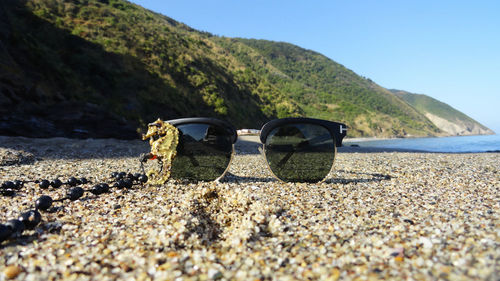 Sunglasses on beach against clear sky