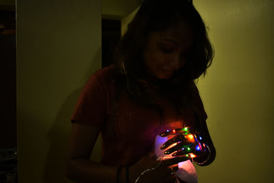 Close-up of young woman holding illuminated lighting equipment