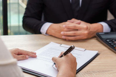 Midsection of man holding paper while sitting on table