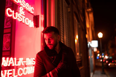 Portrait of young man in city at night