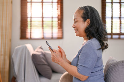 Young woman using phone while sitting at home