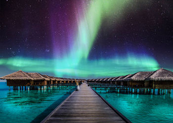 Pier on lake against sky at night