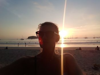 Portrait of man on beach against sky during sunset