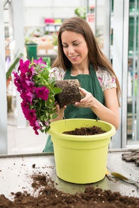 Woman holding flower pot on potted plant