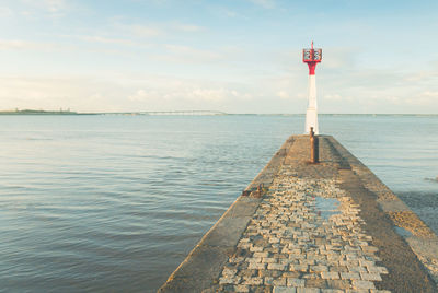 Lighthouse by sea against sky