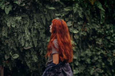 Young woman standing against trees