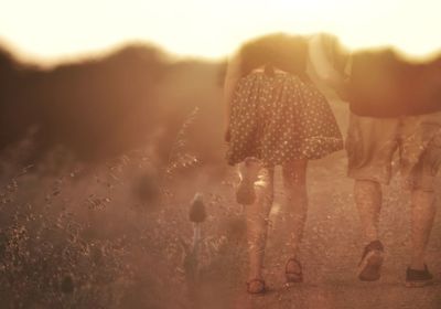 Double exposure of couple walking on field against sunset sky