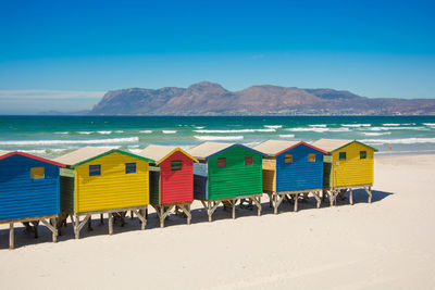 Beach huts by sea against blue sky