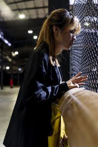 Side view of businesswoman looking through fence at railroad station