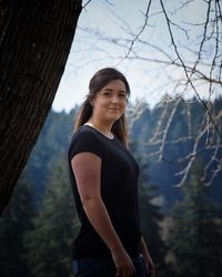 Side view portrait of woman standing against trees