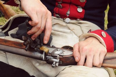 Cropped image of man cleaning gun at field