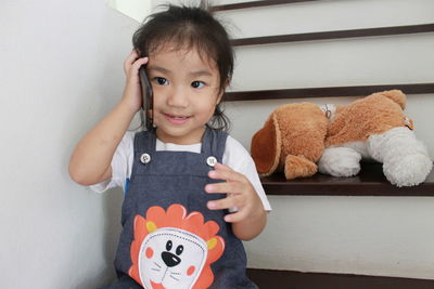 Cute baby girl playing phone cover while sitting on steps at home