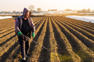 The farmer treats the field from weeds and grass for growing potatoes. use chemicals in agriculture