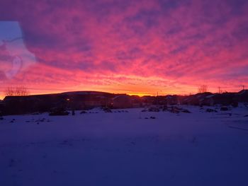 Scenic view of snowcapped landscape against romantic sky at sunset