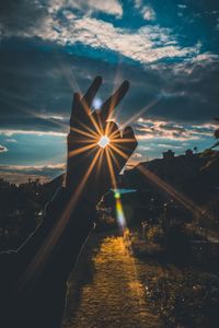 Cropped hand gesturing ok sign against sky during sunset