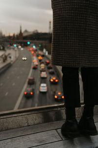 Low section of person standing on road in city