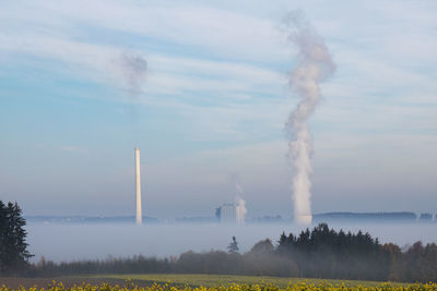 Smoke emitting from factory against sky