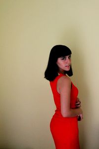 Portrait of smiling young woman standing against white background