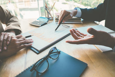 Cropped hands of businessman discussing with male colleague in office