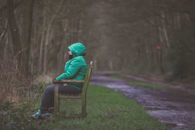 Woman sitting on bench by road