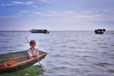 Girl sitting in boat on sea against sky