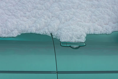 Close-up of snow on turquoise car