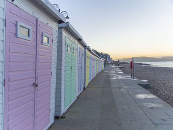 Footpath by sea against clear sky during sunset
