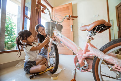 Mother assembling bicycle with daughter at home