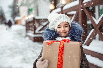 Portrait of smiling girl holding present standing outdoors