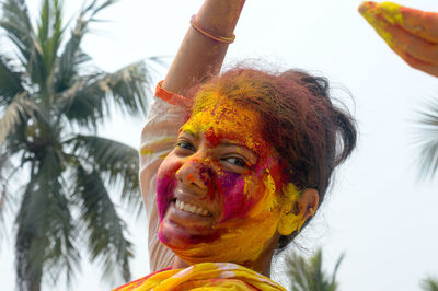 Young indian happy woman with color on face on holi color festival. front view. looking at camera.