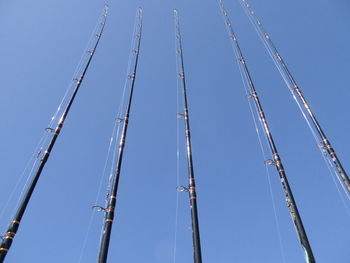 Low angle view of fishing equipment against clear blue sky