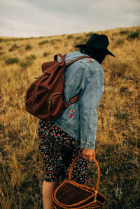 Rear view of person wearing hat standing on field