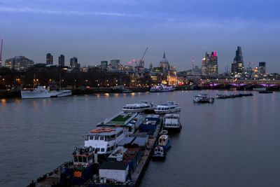Boats sailing in river with city in background