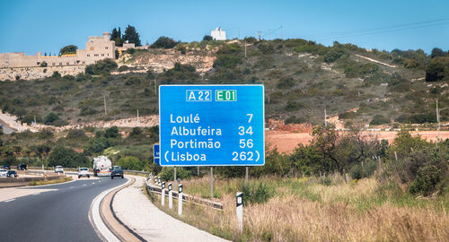 Information sign by road against clear blue sky