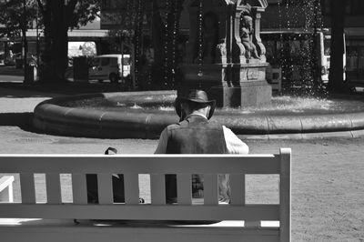 Rear view of man sitting on bench in city