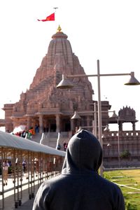 Rear view of man outside temple against building