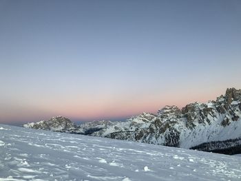 Snow covered landscape against clear sky during winter