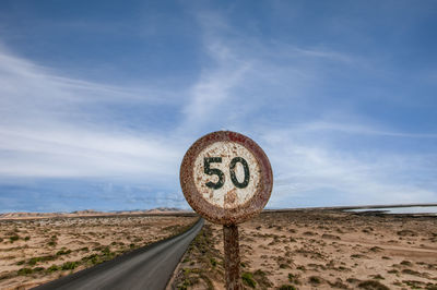 Rusty speed restriction sign on an empty road in the midle of nowhere, 50.