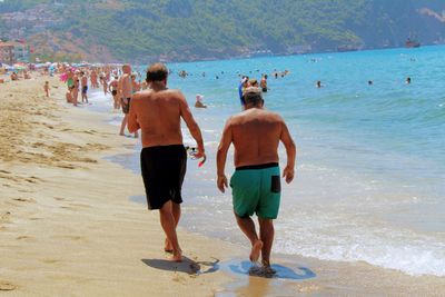 Rear view of men walking on beach