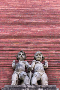 Statue against red brick wall