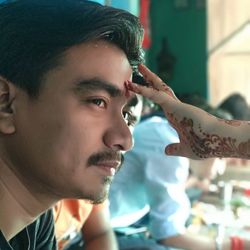 Woman with henna tattoo applying tilaka on forehead of man