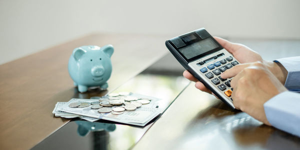 Cropped hand using calculator on table