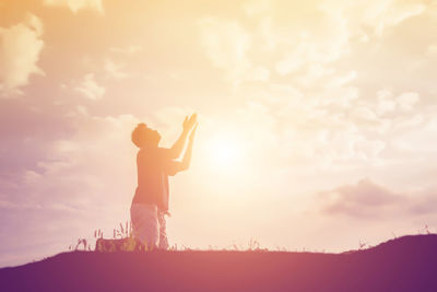 Silhouette man standing on field against sky during sunset