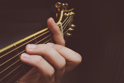 Close-up of person playing guitar against black background