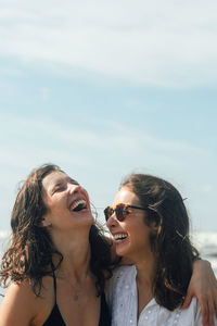 Young woman smiling against sky