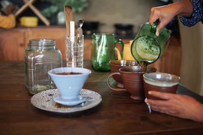 Midsection of person holding drink with glass on table