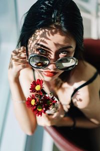 Portrait of young woman holding red flowers