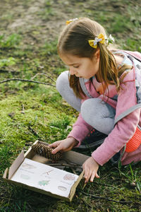 Young woman reading book while sitting on field