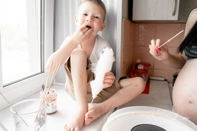 Midsection of pregnant mother preparing food with son at home