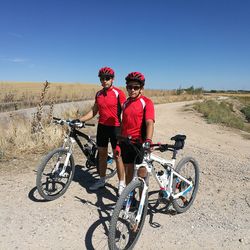 Father and son with bicycles on landscape against clear sky